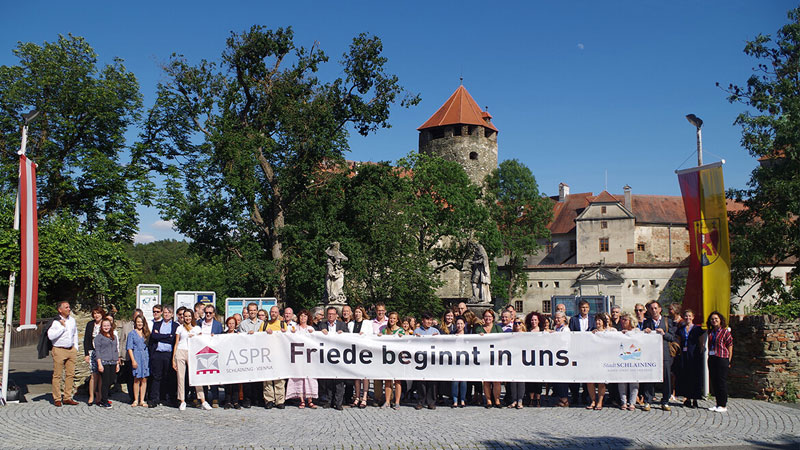 Gruppenfoto mit Banner "Friede beginnt in dir" vor der Friedensburg Schlaining