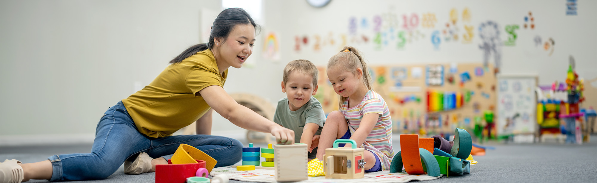 Pädagogin mit zwei Kindern am Boden spielend