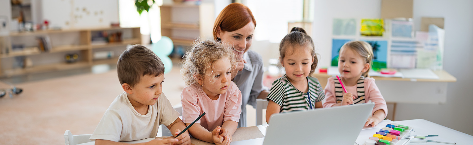 Elementarpädagogin mit Kindern vor einem Laptop