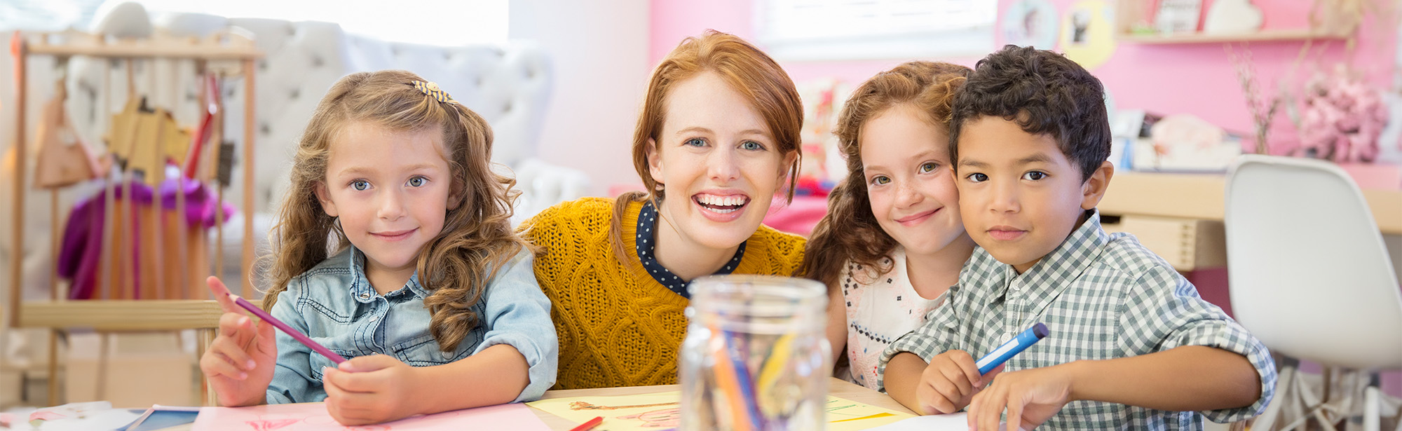 Pädagoging mit Kindern an einem Zeichentisch